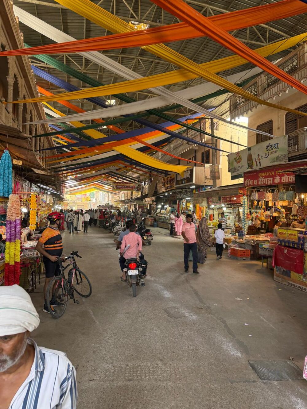 A narrow, crowded market lane under colourful canopies