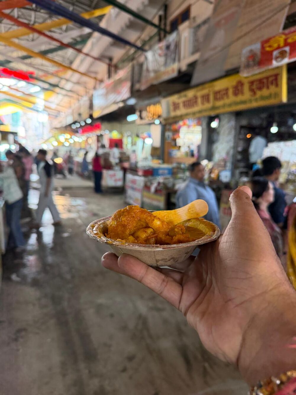 A hand holding a leaf bowl of kachori in the market