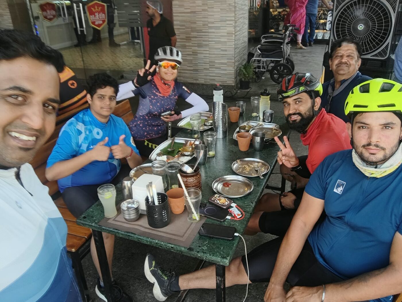Riders at a table with thalis, giving thumbs up